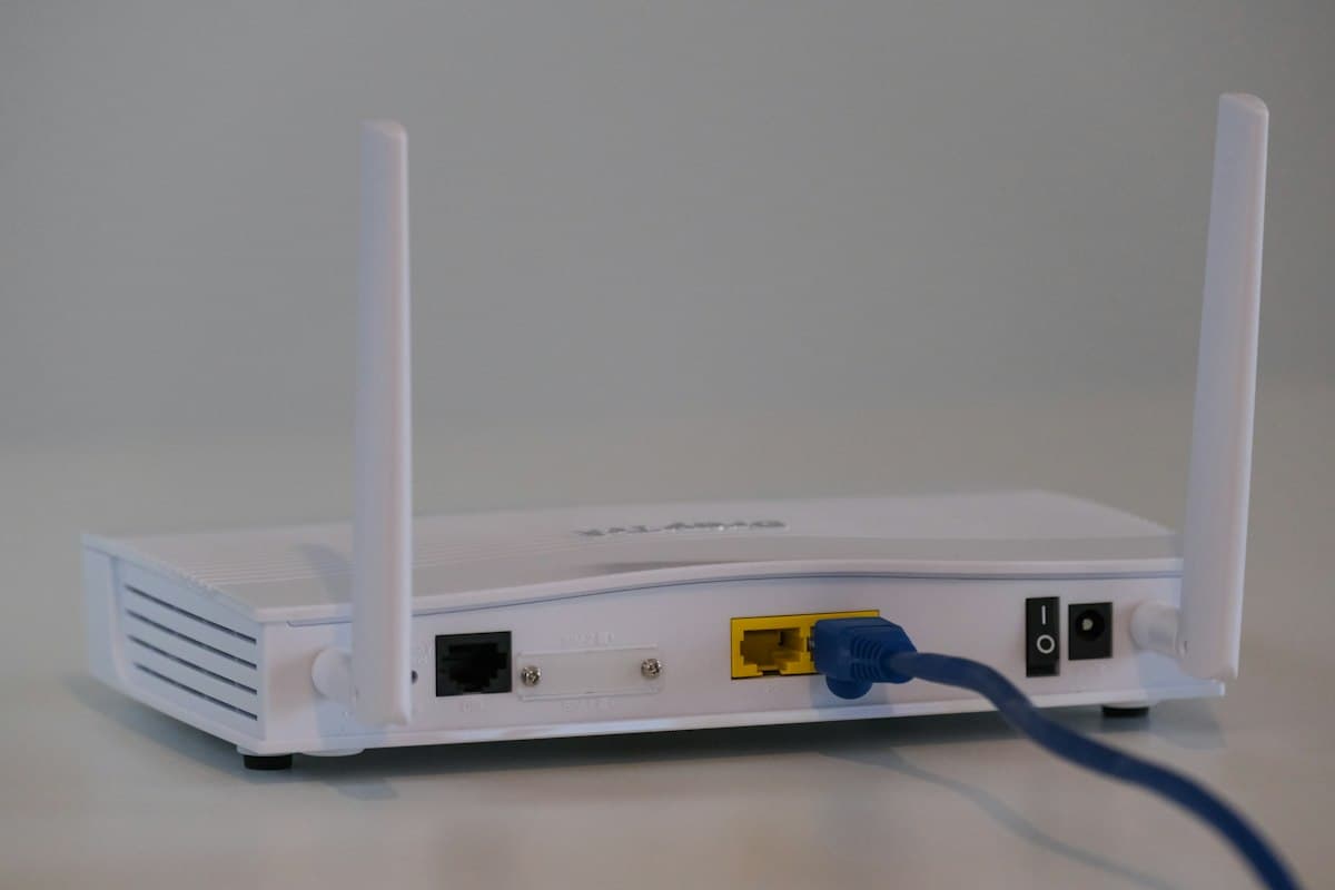 Witte wifi-router met antennes en een aangesloten netwerkkabel