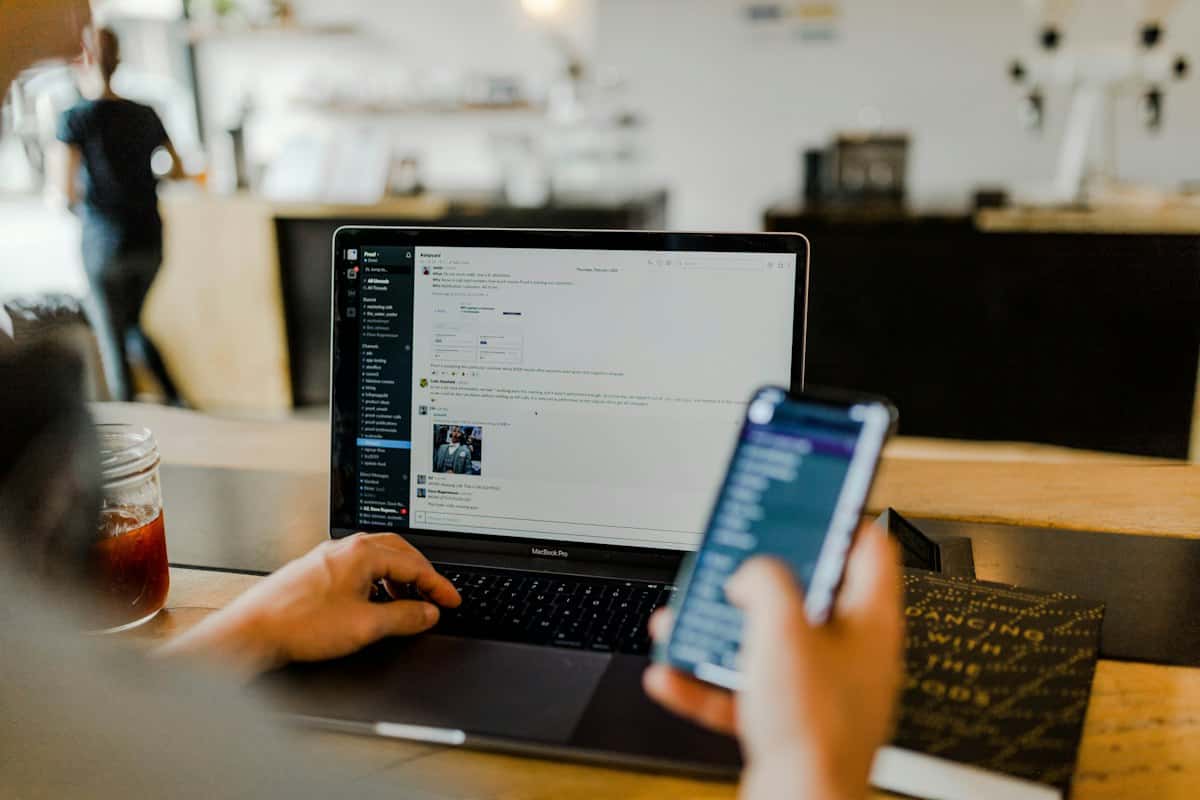 Persoon met een laptop en een smartphone in de hand